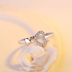 Macro shot of silver adjustable open ring with heart designs on a white rose