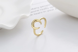Detailed view of an adjustable golden crescent moon ring on a minimalist ceramic plate