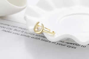 Macro shot of minimalist golden crescent ring on white porcelain and message card