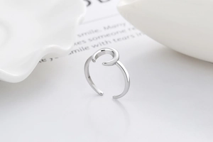 Macro side view of polished silver minimalist moon open ring on white ceramic background