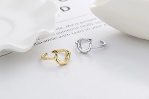 Detailed view of adjustable gold and silver moon-shaped rings on a minimalist white ceramic dish