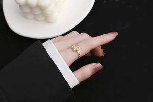 Detail of a minimalist gold crescent moon ring on a model against a luxury background