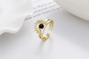 Detail shot of golden sunburst ring with black gemstone on dual-band adjustable ring