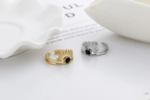 Detailed view of adjustable sunburst rings in gold and silver with black gemstones