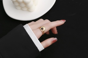Detail of sunburst ring with black center stone worn on hand against dark background