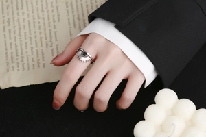 Detailed view of silver sunburst ring with black gemstone on a model hand