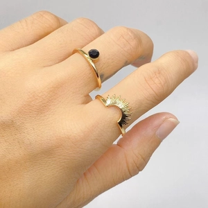 Detail of gold-plated sunburst and black gemstone ring set worn on finger