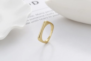 Nahaufnahme eines minimalistischen goldenen quadratischen Rings auf weißem Hintergrund