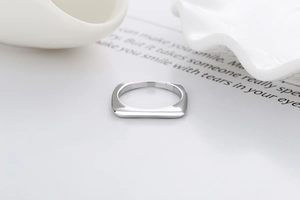 Makroaufnahme eines silbernen quadratischen Rings mit polierter Oberfläche auf weißem Grund