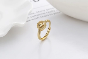 Détail d'une bague dorée ajustable avec un design circulaire et une bande gravée