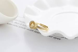 Détail d'une bague dorée rotative avec perles texturées sur une assiette en céramique