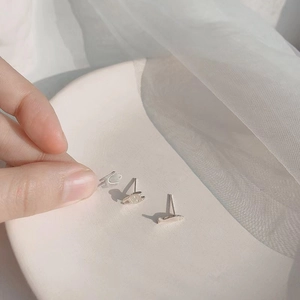 Macro shot of three delicate silver fish-shaped studs on a minimalist white plate