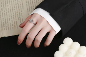 Gros plan d'une bague double anneau argentée sertie de zircons et d'une perle