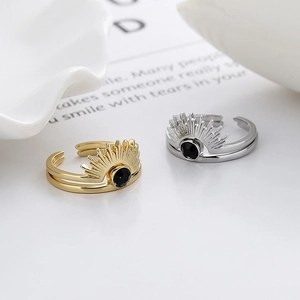 Minimalist sunburst rings in gold and silver set with black stone on white background