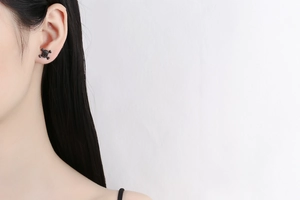 Close-up of black punk skull stud earrings with pavé crystals on model's ear