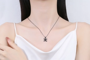 Close-up of punk style black skull pendant necklace with dark crystals on female model