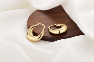 Detail of chunky gold waterdrop hoop earrings with high-polish mirror finish and secure clasp