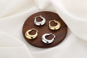 Detailed view of polished hollow crescent hoop earrings in gold and silver finishes