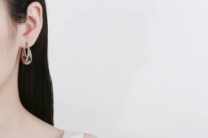 Close-up of polished silver water-drop hoop earrings worn for a sleek fashion look