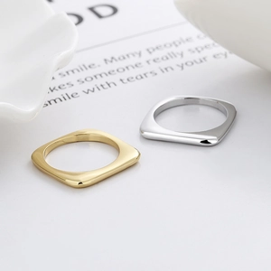 Minimalistische quadratische Paar-Ringe in poliertem Gold und Silber auf weißem Grund