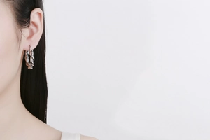 Gros plan d'une boucle d'oreille créole torsadée en argent avec un design de corde polie