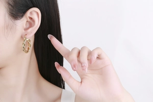 Gros plan d'un modèle portant des boucles d'oreilles créoles dorées torsadées