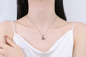 Close-up of vintage silver skull pendant on a fine chain worn over white satin