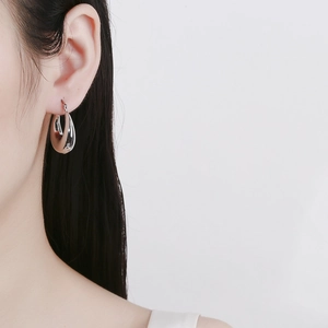 Polished silver hollow crescent hoop earrings for women shown on a fashion model