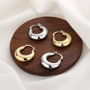 Polished 18K gold and silver hollow crescent hoop earrings displayed on a wood tray