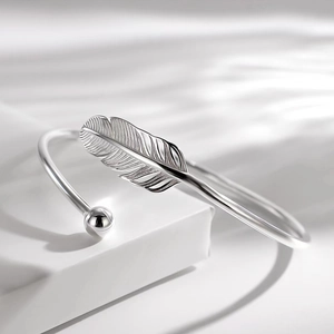 Elegant silver feather open cuff bracelet with detailed texture on minimalist white background