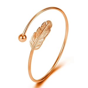 Close-up of rose gold minimalist feather open bangle with refined leaf texture