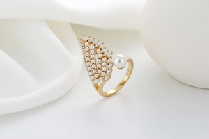 Detail of golden wing ring with micro-set zircon and white pearls on silk cloth
