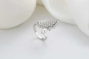 Detail of silver wing ring with sparkling zircons and pearls on elegant white fabric