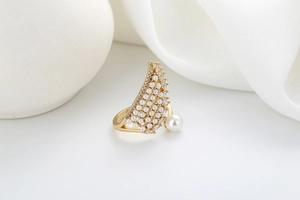 Detail of gold wing ring with micro-set zircons and pearls on minimalist white background