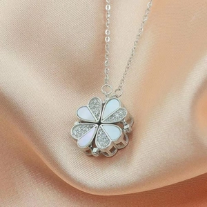 Macro detail of silver clover pendant with white shell and magnetic folding mechanism
