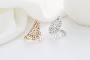 Detailed view of gold and silver wing-shaped open rings with pearls and zircons