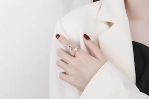 Close-up of a golden wing ring with micro-set zircons and a pearl on a model's finger