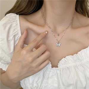 Close-up of double-layered silver necklace with sparkling butterfly and flower pendants