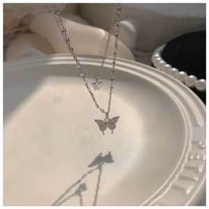 Detail shot of double-layered silver necklace featuring sparkling zircon butterfly charms