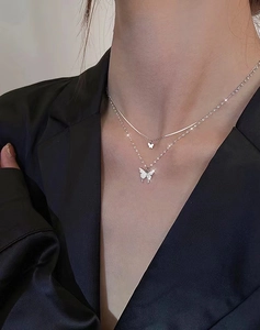 Close-up of double-layer silver necklace with sparkling butterfly pendants on a model