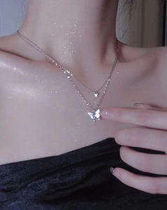 Close-up of double-layered butterfly pendant necklace with shimmering crystals on neck