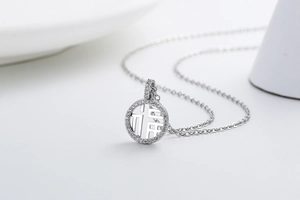 Macro shot of silver circular pendant with hollow Fu character and paved cubic zirconia