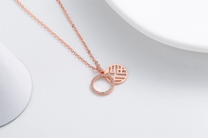 Macro detail of rose gold double pendant necklace with CZ inlay and Fuxi character