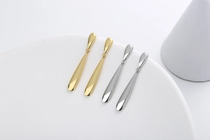 Polished gold and silver teardrop earrings with mirror finish on white display stand