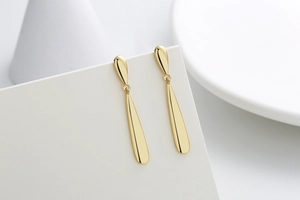 Macro view of long gold geometric teardrop earrings with a high-polished metallic finish