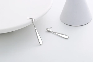 Close-up of minimalist silver water drop earrings with smooth metallic finish on white display