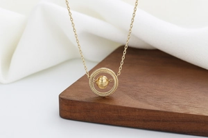 Macro detail of golden spinning bead pendant with delicate geometric textured double rings
