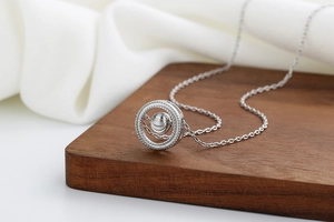 Close-up of minimalist silver hoop pendant necklace with textured bead on wooden stand