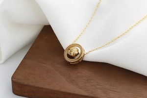 Macro shot of gold geometric ring pendant with textured bead on elegant O-chain