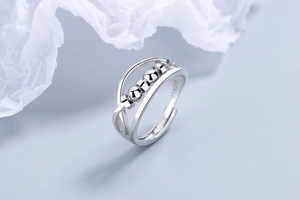 Macro detail of S925 sterling silver ring featuring three sliding beads on a double cross band